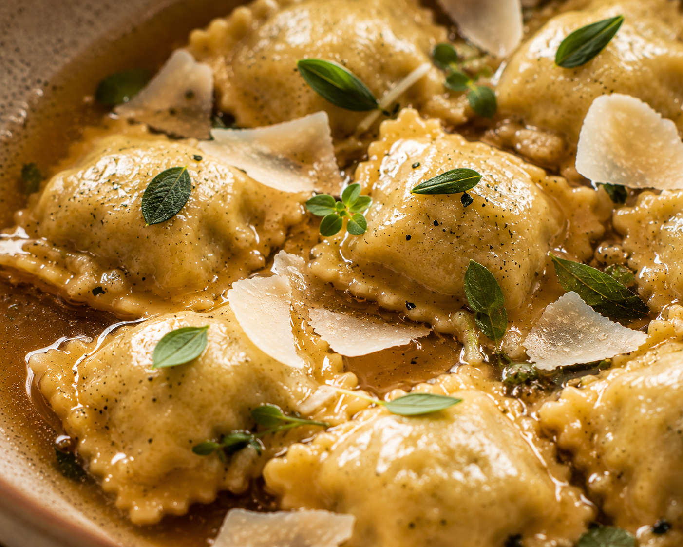 Close-up of agnolotti del plin glossed with brown butter, sage leaves and shaved Parmigiano